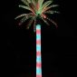 Glowing red and green Christmas lighted outdoor artificial palm tree at dusk